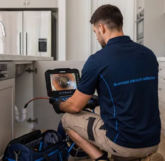 Plumber clearing a blocked toilet in a Hurstville bathroom